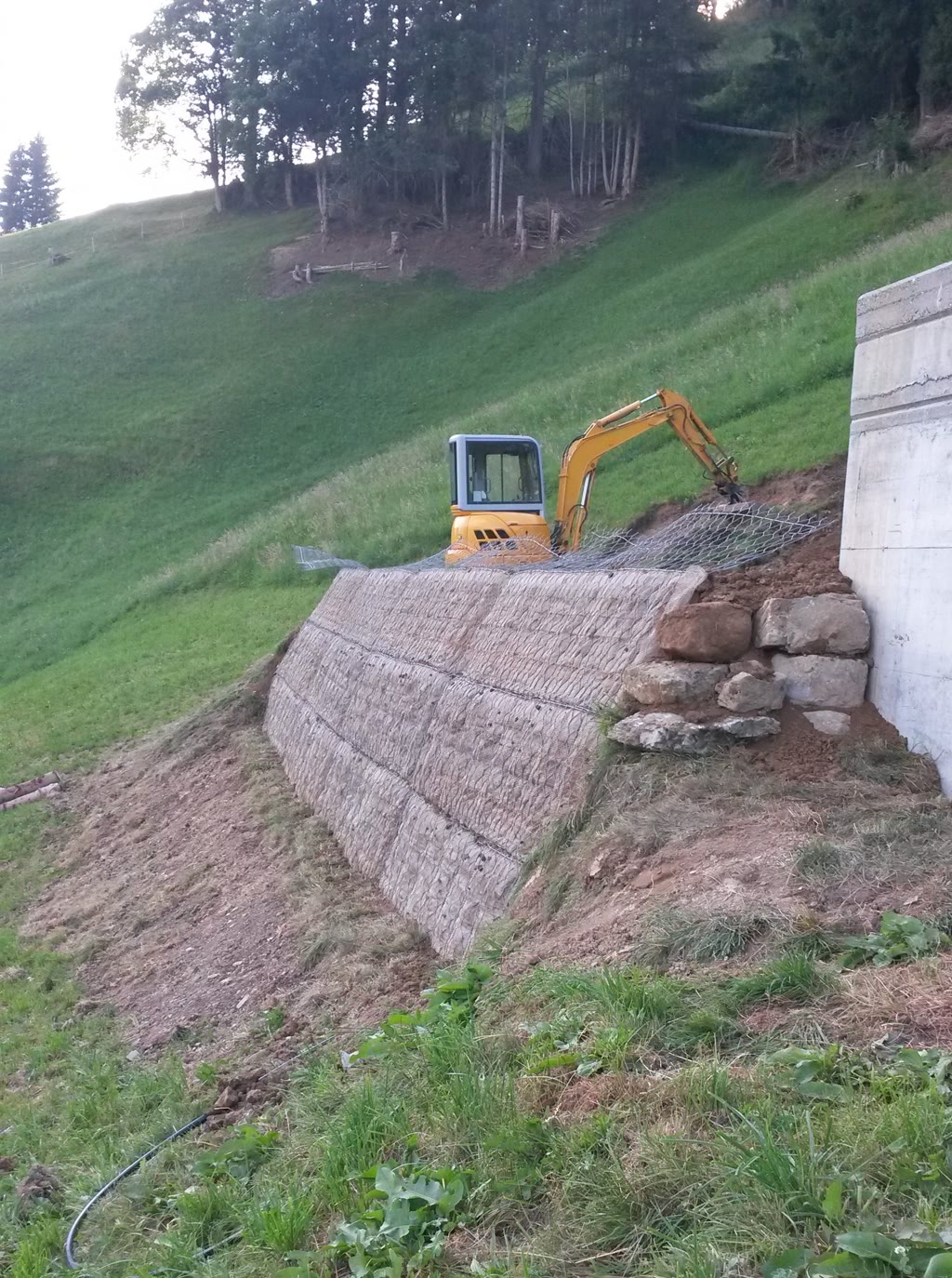 Steilböschung mit Steinkorbfront, Bagger beim Einbau